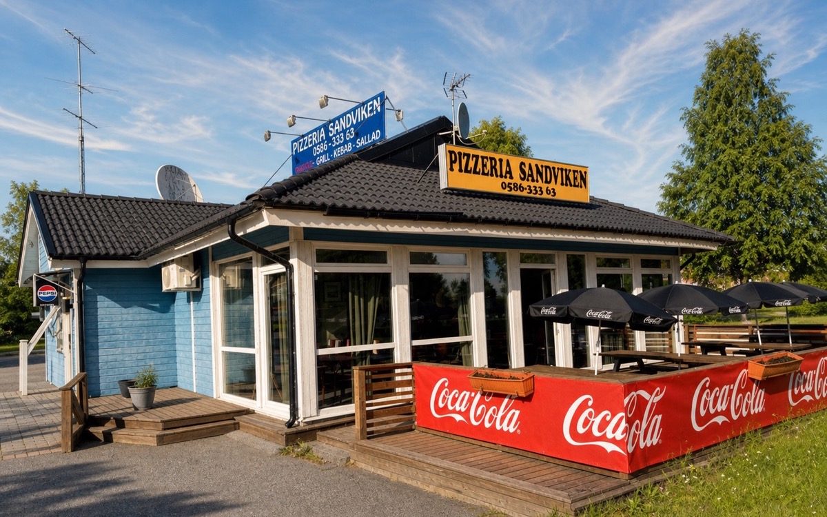 Sandvikens Pizzerias blå restaurangbyggnad med uteservering och tydlig skylt